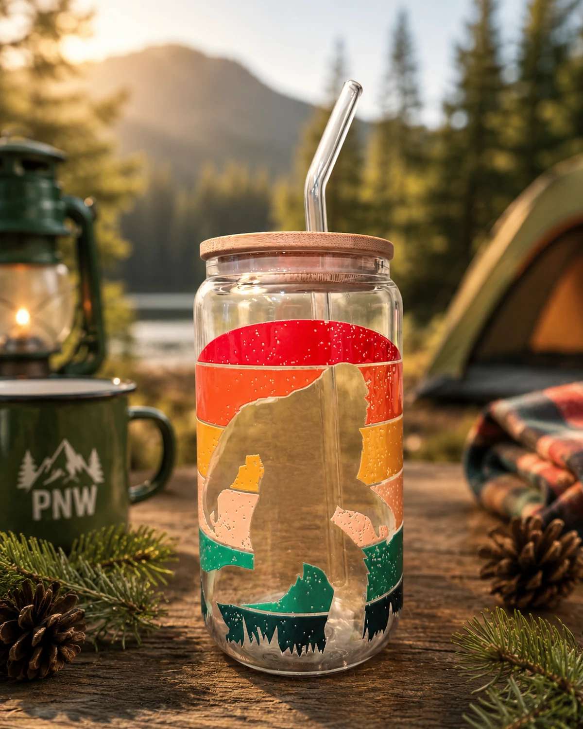 PNW Sasquatch glass tumbler with bamboo lid and reusable straw in an evergreen camping setting